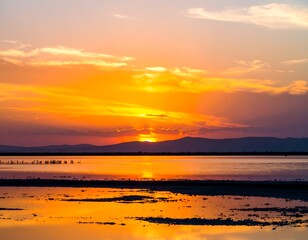 Vibrant sunset over calm water, reflecting fiery colors in the shallows