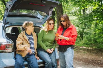 Elderly happy european woman mother and adult mature daughters traveling together by car
