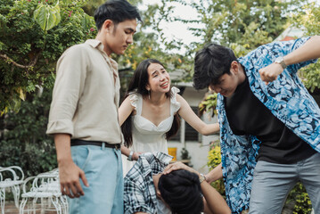 A desperate young Southeast Asian woman pleads emotionally as two callous bullies beat a crouched young man, who shields himself on the ground during a violent group attack outdoors.