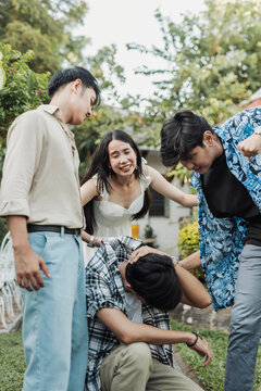 A distraught young Southeast Asian woman cries out helplessly as two remorseless bullies continue physically assaulting her male friend, who cowers in pain on the ground.