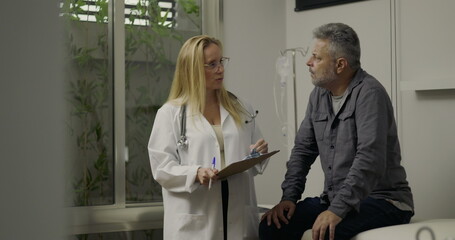 Middle-aged male patient talking to doctor during medical appointment in clinic, discussing health...