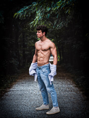 Strong young man standing in a forested pathway during daytime