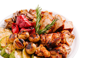 Grilled meat platter with vegetables and herbs presented on a white plate