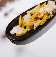 Crispy seasoned potato fries topped with cheese on a sleek black plate