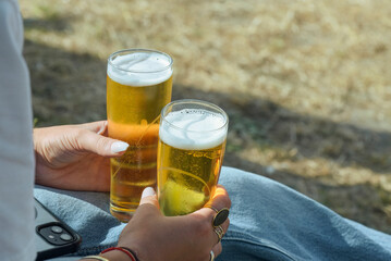female person holding a beer glass filled with beer in both hands
