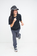 An upbeat young Asian woman captured mid-run with one leg lifted, smiling brightly and looking to the side, expressing joy and playful motion. Isolated on a white background.