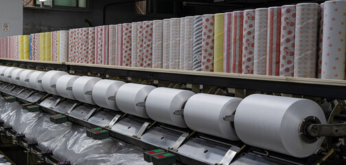 Spools of industrial yarn arranged on racks in a textile manufacturing facility, showcasing...