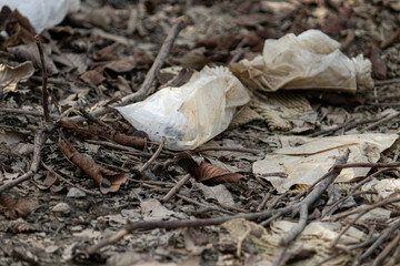 Plastic trash and nylon bags discarded among dry leaves. Concept of environmental pollution and ecological crisis