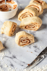 Cutted roll of dough on white marble background. Making cinnamon rolls process. Cinnabon preparation