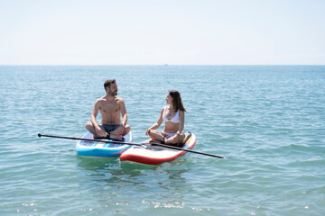 Couple relaxing on paddle boards in tranquil ocean waters