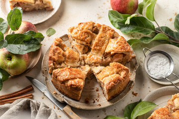 Homemade cutted Apple Pie with fresh apples on textured background. Thanksgiving traditional dessert, autumn baking, recipe