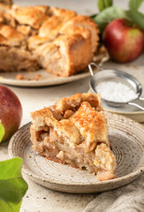 Slice of homemade Apple Pie with fresh apples on textured background. Thanksgiving traditional dessert, autumn baking, recipe