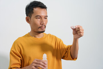 A man carefully uses eye drops or an eye wash solution, focusing on his eye health and personal hygiene routine to maintain clear and comfortable vision.
