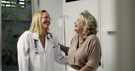 Female doctor and older woman laughing together in clinic during friendly checkup, illustrating...