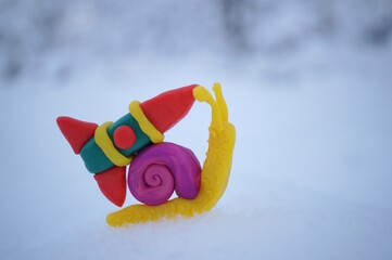 A toy snail with a rocket on a background of snow.