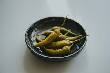 Fresh Green Chili Peppers Arranged in a Rustic Black Plate on Light Background