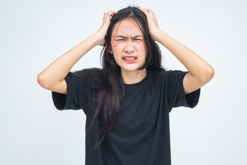 A tormented young Asian woman scratching her irritated head with both hands while grimacing,...