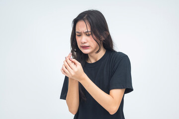 A worried young Asian woman looking sadly at her burned finger, showing pain and concern with a...