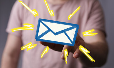 Stock photo of a hand holding a digital email icon with bright yellow streaks, symbolizing fast...