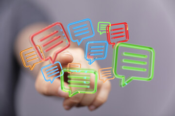 Hand interacting with colorful speech bubbles, symbolizing communication, messaging, and online...