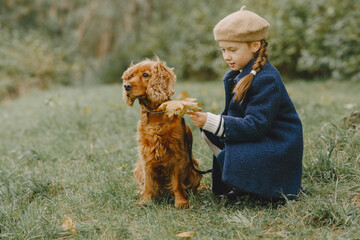 Little girl walks in autumn forest with a dog