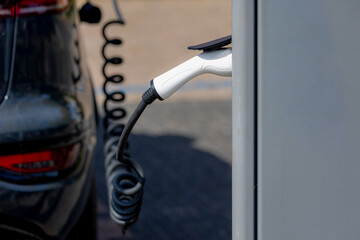Selective focus of power supply connect to electric vehicle for charging battery, Charging an electric car in public station by the street along the canal, Green energy, Amsterdam, Netherlands.