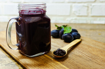 Homemade Plum Jam in Glass Jar with Fresh Plums on Wooden Board