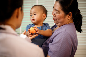 An overweight Asian woman brings her one-year-old son to consult a health expert in a private office. The scene emphasizes family care, professional guidance, wellness improvement