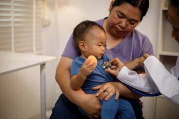 An overweight Asian woman brings her one-year-old son to consult a health expert in a private office. The scene emphasizes family care, professional guidance, wellness improvement
