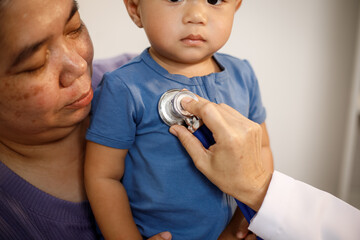 An overweight Asian woman brings her one-year-old son to consult a health expert in a private office. The scene emphasizes family care, professional guidance, wellness improvement