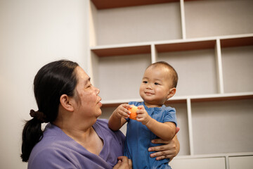 overweight Asian woman joyfully plays with her one-year-old son in a private room, highlighting love, bonding, happiness, and emotional wellness.