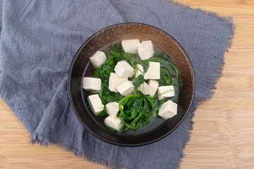 Pea tip and tofu soup in a porcelain bowl