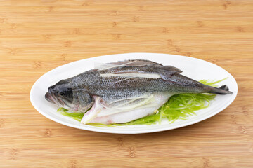 Fresh steamed sea bass ingredients in a porcelain plate