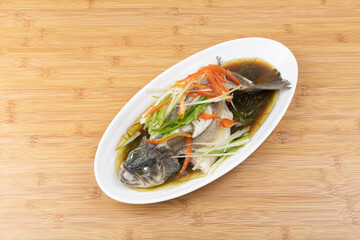 Steamed sea bass in a white porcelain plate