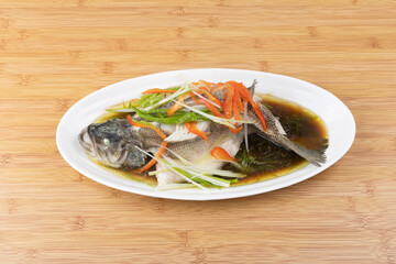 Steamed sea bass in a white porcelain plate