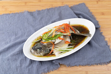 Steamed sea bass in a white porcelain plate