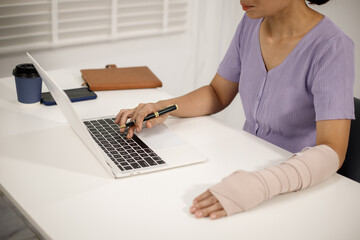 A person in a purple shirt sits at a desk, holding a blue smartphone in their left hand, while...