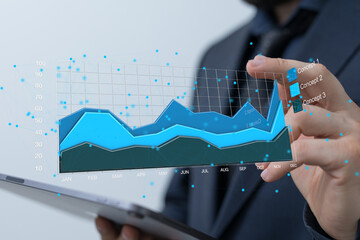 Stock photo of a businessman reviewing financial charts and graphs on a digital tablet.