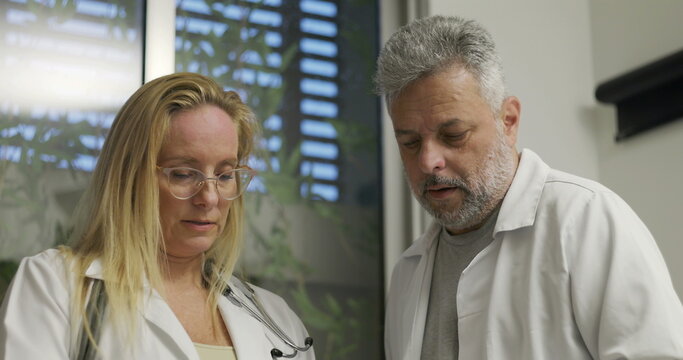 Doctors reviewing and discussing X-ray results during clinical diagnosis in hospital setting with focused expressions and collaborative teamwork - Powered by Adobe