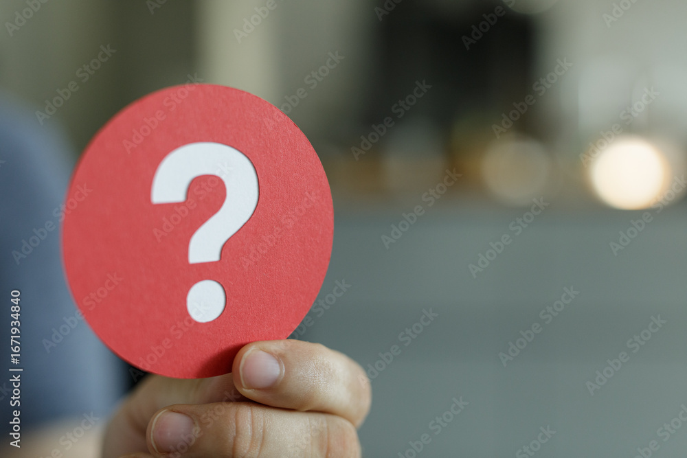 Poster close-up image of a hand holding a red circle with a white question mark. perfect for concepts of qu
