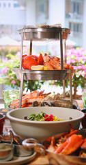 Seafood tower with lobster, prawns, mussels at outdoor restaurant, vibrant ambiance. Fresh seafood platter, coastal dining concept, culinary indulgence, summer. Vertical