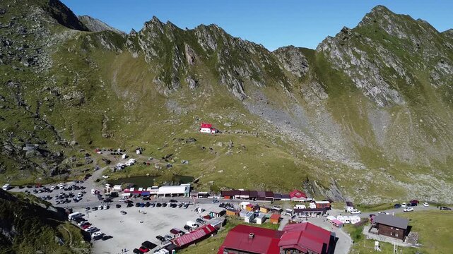 Drone shot of mountain village with red-roof houses and solar panels above winding road
