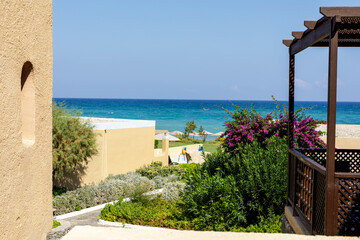Stunning sea view from a resort patio.  Relaxing vacation scene with lush greenery and beautiful...