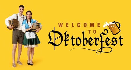 Young couple in traditional German clothes with barrels of beer and Bavarian flag on yellow...
