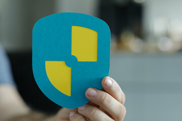 Person holding a paper shield with a yellow design.  Protection, security, safety concept.