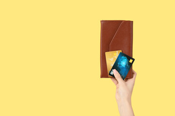 Woman with credit cards and wallet on yellow background