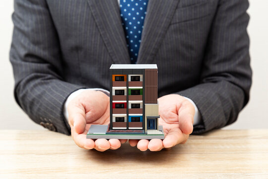 マンションの模型を持つサラリーマン