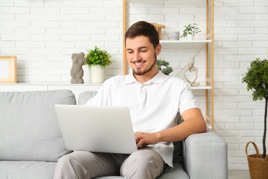 Handsome young man using laptop on online date at home