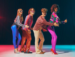 Retro disco group dancing in bright costumes with energetic vibe. Concept of pop culture celebration, vintage party lifestyle, nostalgia branding, and colorful fashion promotion.