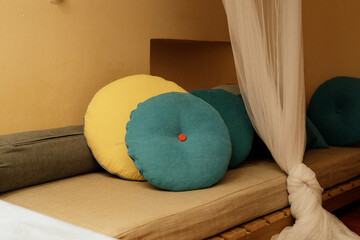 Relaxing bedroom scene with round pillows in teal and yellow on a beige daybed.  Perfect for home...